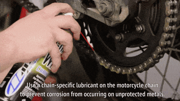 Механик смазывает мотоциклетную цепь.