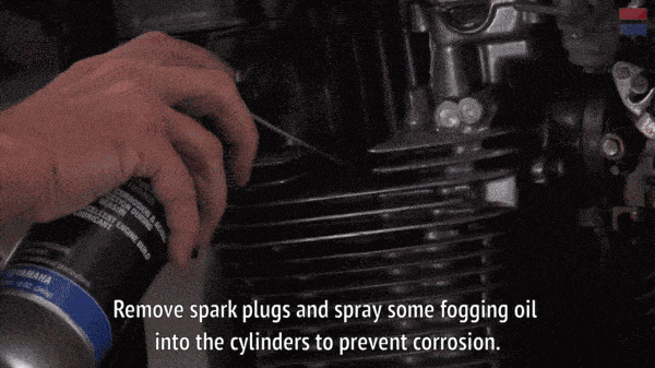 Механик распыляет запотевающее масло в цилиндры мотоцикла.