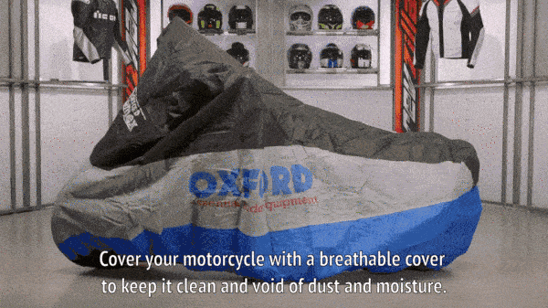 Механик кладет мотоцикл на кусок картона в качестве барьера от влаги и накрывает мотоцикл.