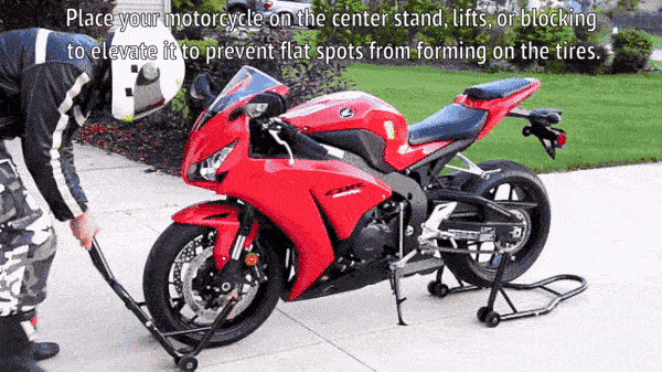 Владелец мотоцикла использует центральную подставку, чтобы поднять мотоцикл и предотвратить появление проколов на шинах.