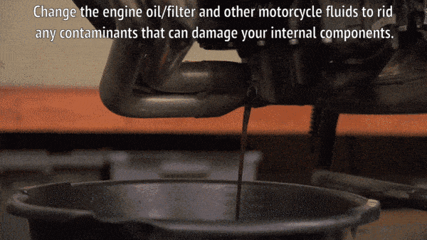 Механик сливает моторное масло с мотоцикла.